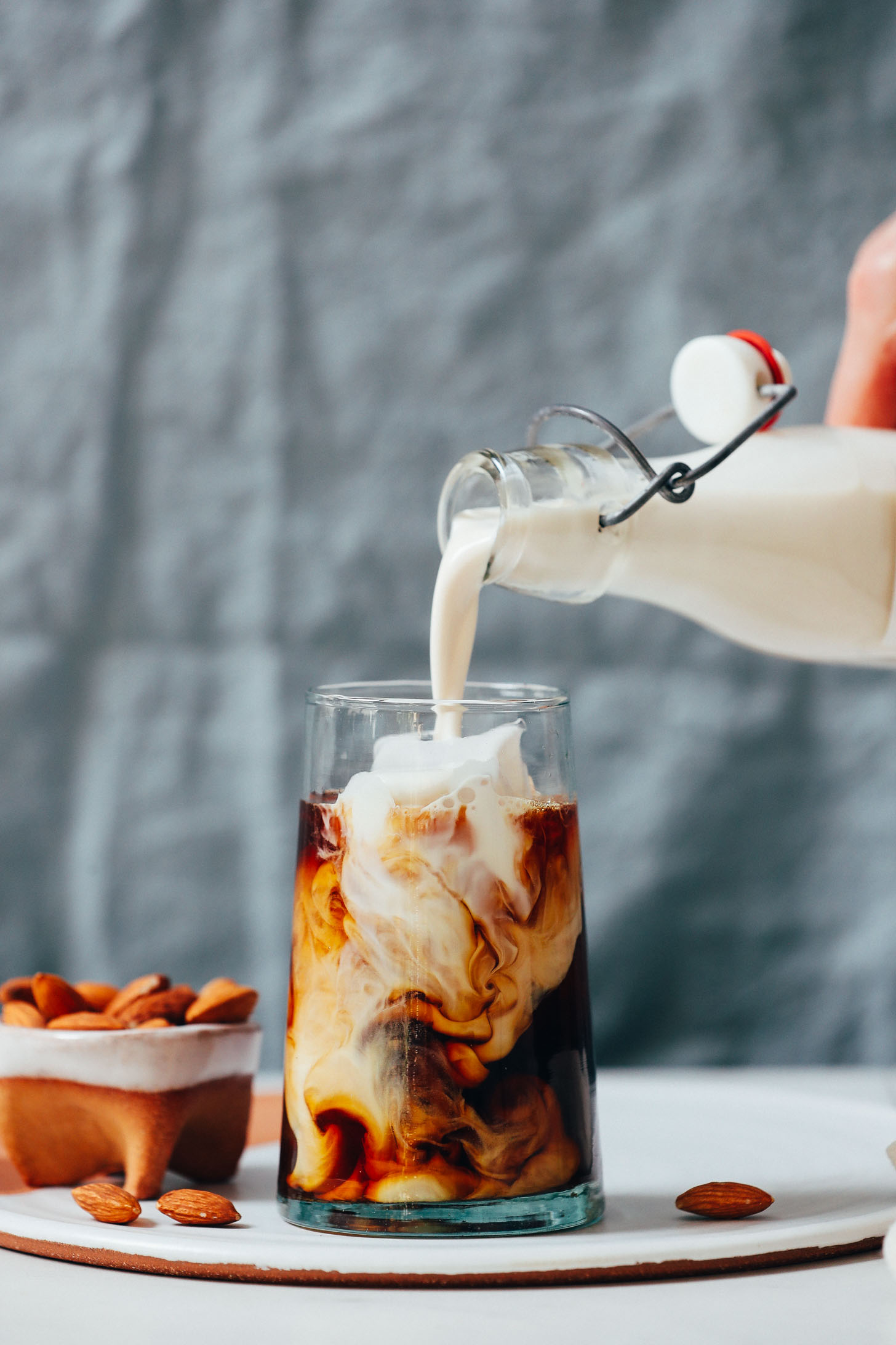 Pouring Almond Milk Coffee Creamer into a glass of iced coffee