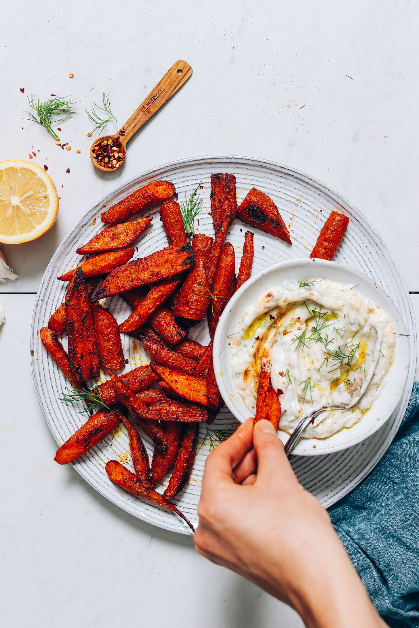 Dipping a roasted carrot slice into a bowl of Zesty Dairy-Free Yogurt Dip