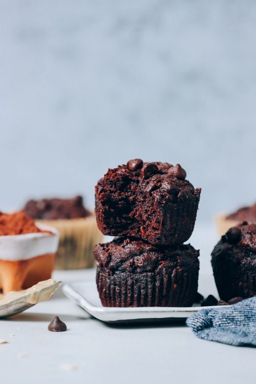 Stack of Banana Chocolate Muffins next to a bowl of cocoa powder