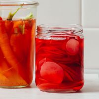 Jar of Quick Pickled Radishes next to a jar of pickled carrots