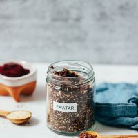 Jar and bowl of homemade za'atar seasoning beside ingredients used to make it