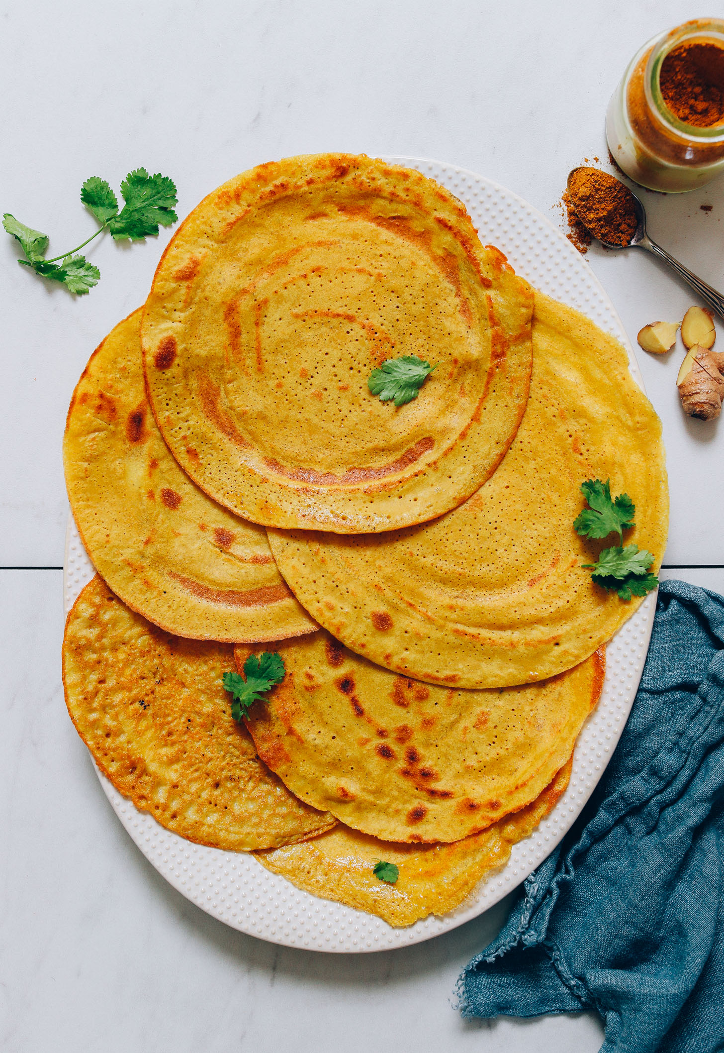 Platter of savory Moong Dal Dosas with fresh cilantro, ginger, and curry powder
