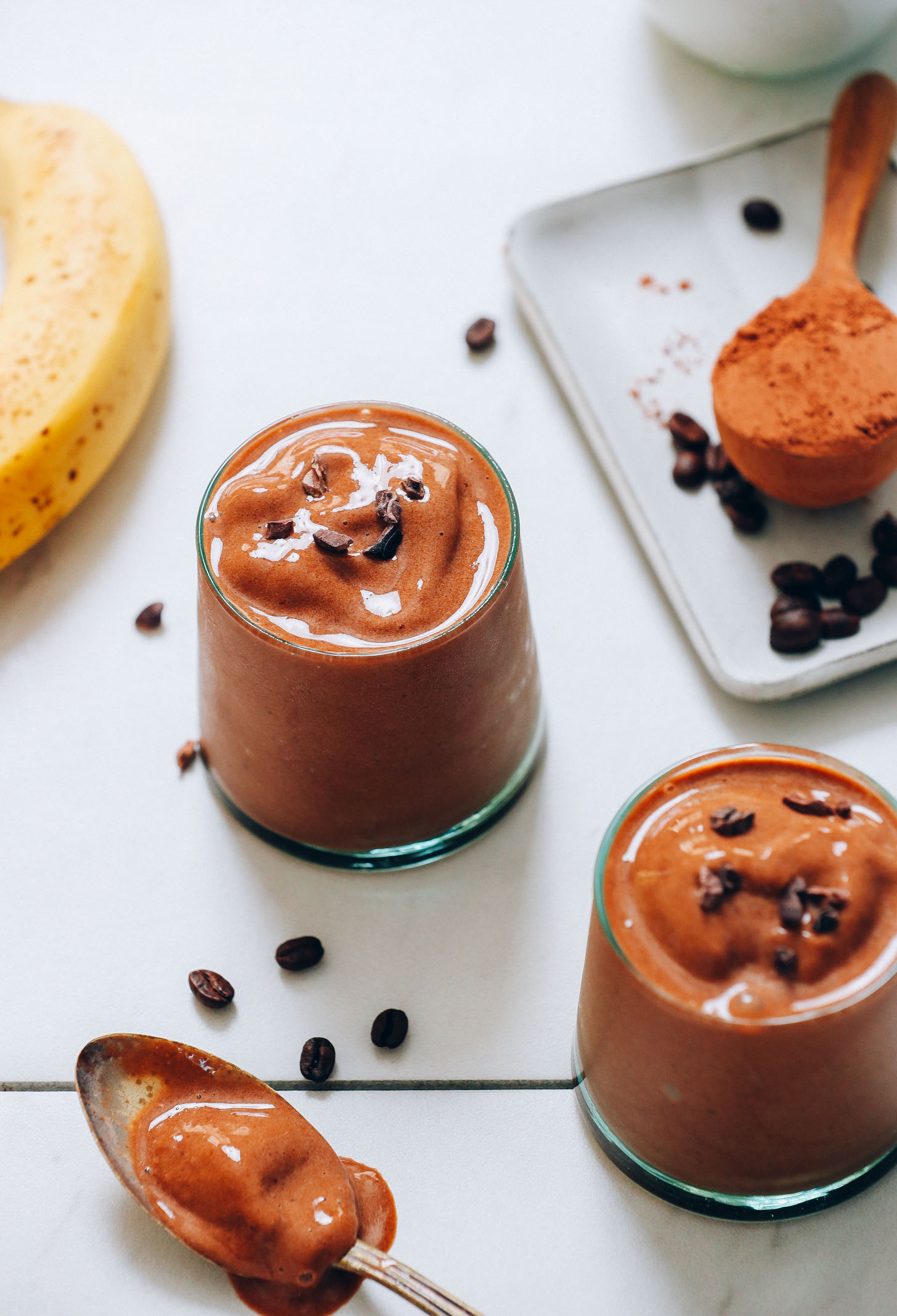 Glasses of our Creamy Cold Brew Smoothie Recipe surrounded by ingredients used to make it