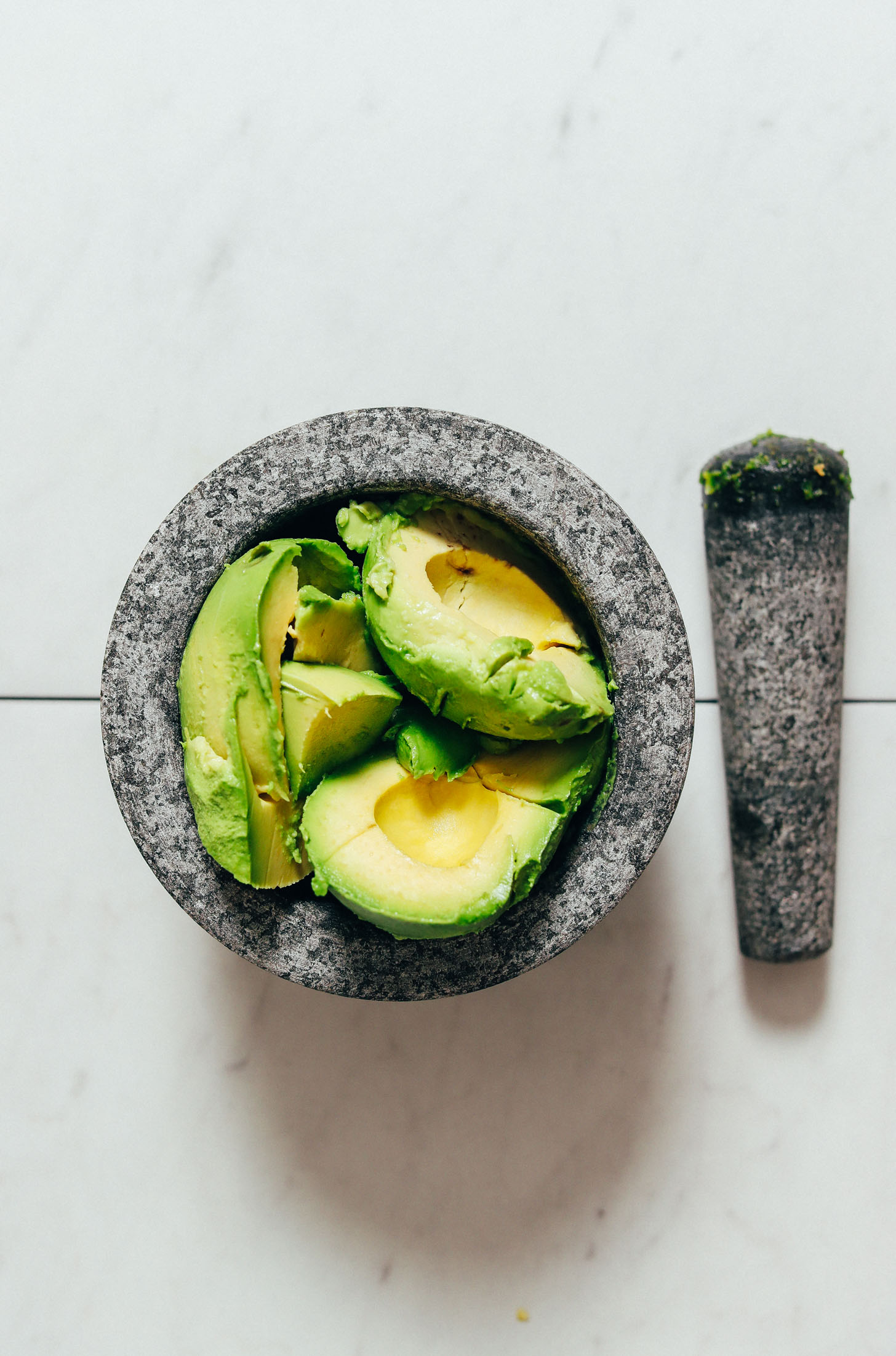 Avocados in a mortar and pestle for making homemade guacamole