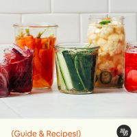 Jars of Quick Pickled Vegetables on a white tile background