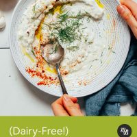 Stirring dill into a bowl of dairy-free yogurt sauce