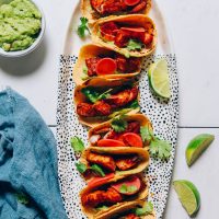 Platter filled with Spicy Baked Fish Tacos beside guacamole and lime wedges