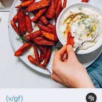 Dipping a Moroccan Roasted Carrot into a bowl of Yogurt Dill Sauce
