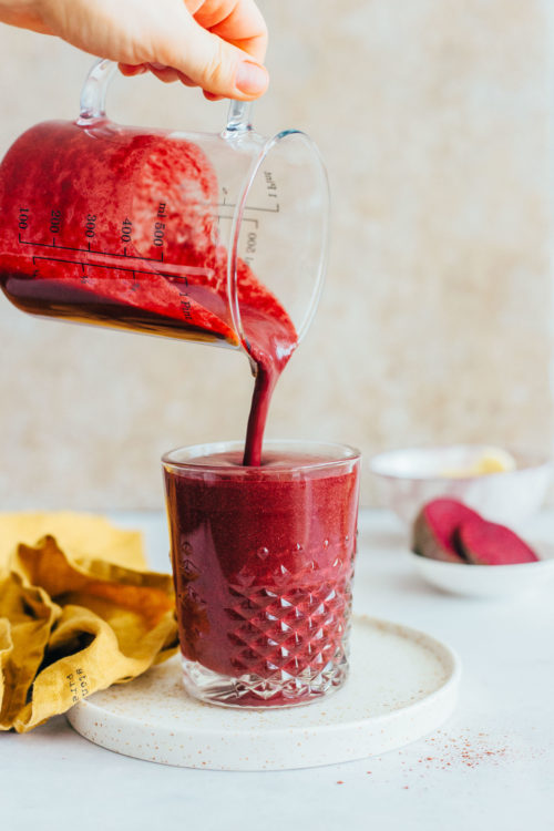 Pouring a red velvet cake smoothie into a glass
