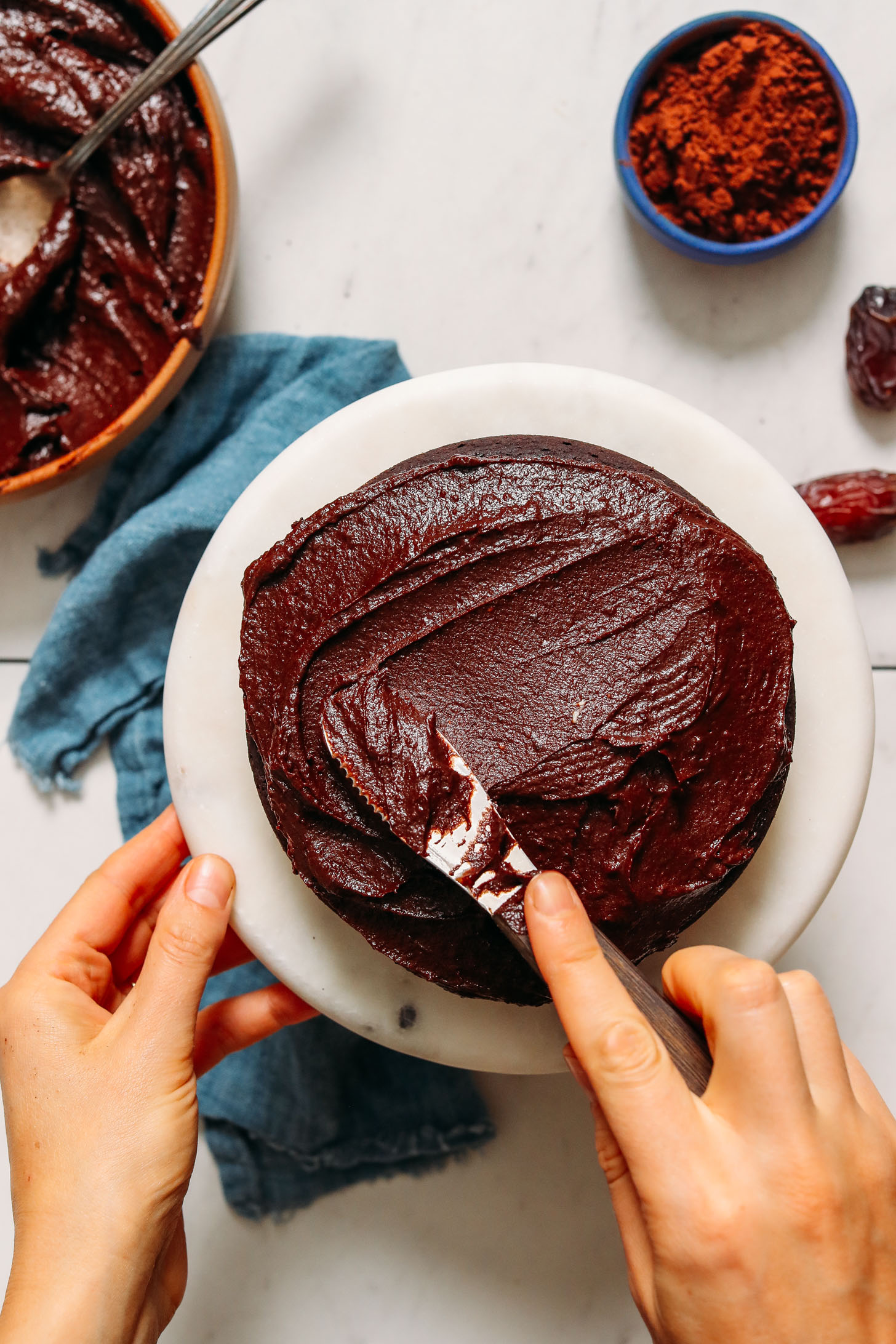 Spreading vegan chocolate frosting onto a chocolate cake