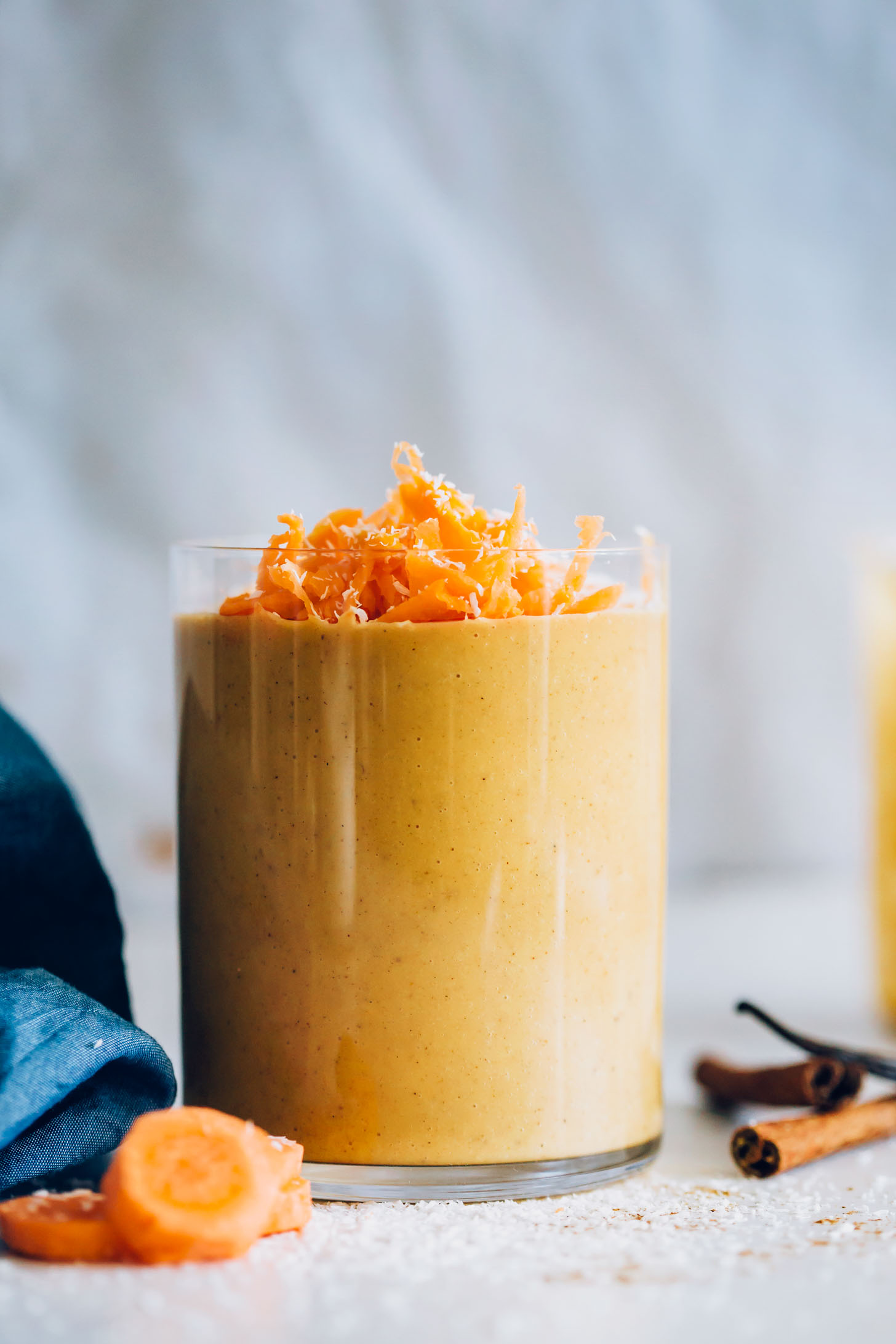 Glass of our Creamy Carrot Cake Smoothie topped with shredded carrot and coconut