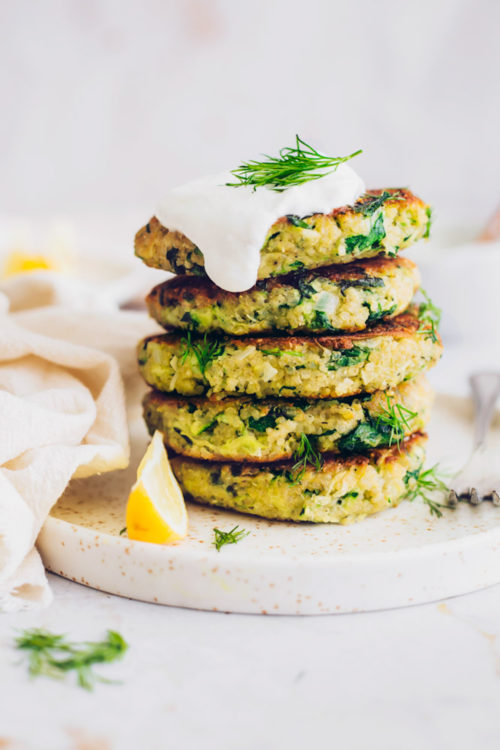 Stack of vegan zucchini fritters topped with coconut yogurt and dill