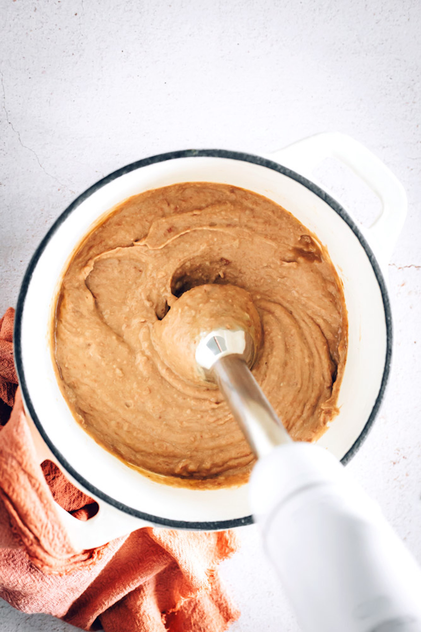 Immersion blender in a pot of Creamy Refried Beans