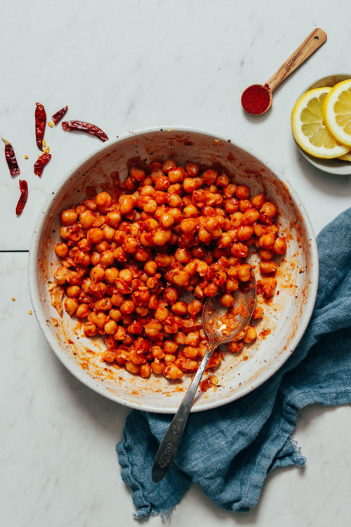 Bowl of Harissa Marinated Chickpeas next to lemons and spices