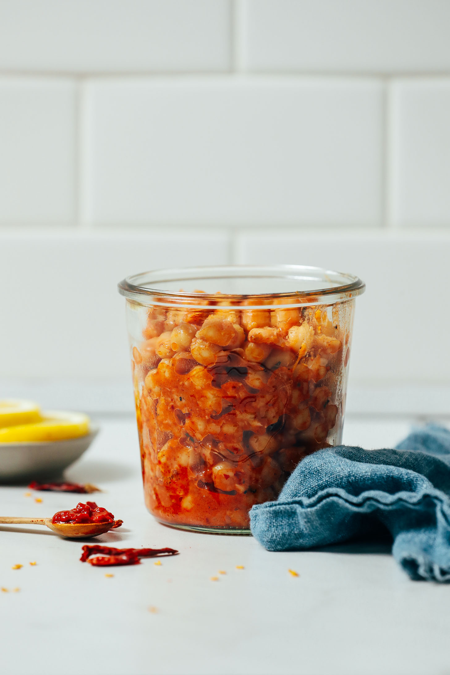 Spoonful of harissa paste next to a jar of Harissa Marinated Chickpeas