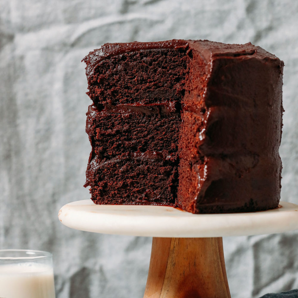 Partially sliced oil free Gluten Free Chocolate Cake on a cake stand