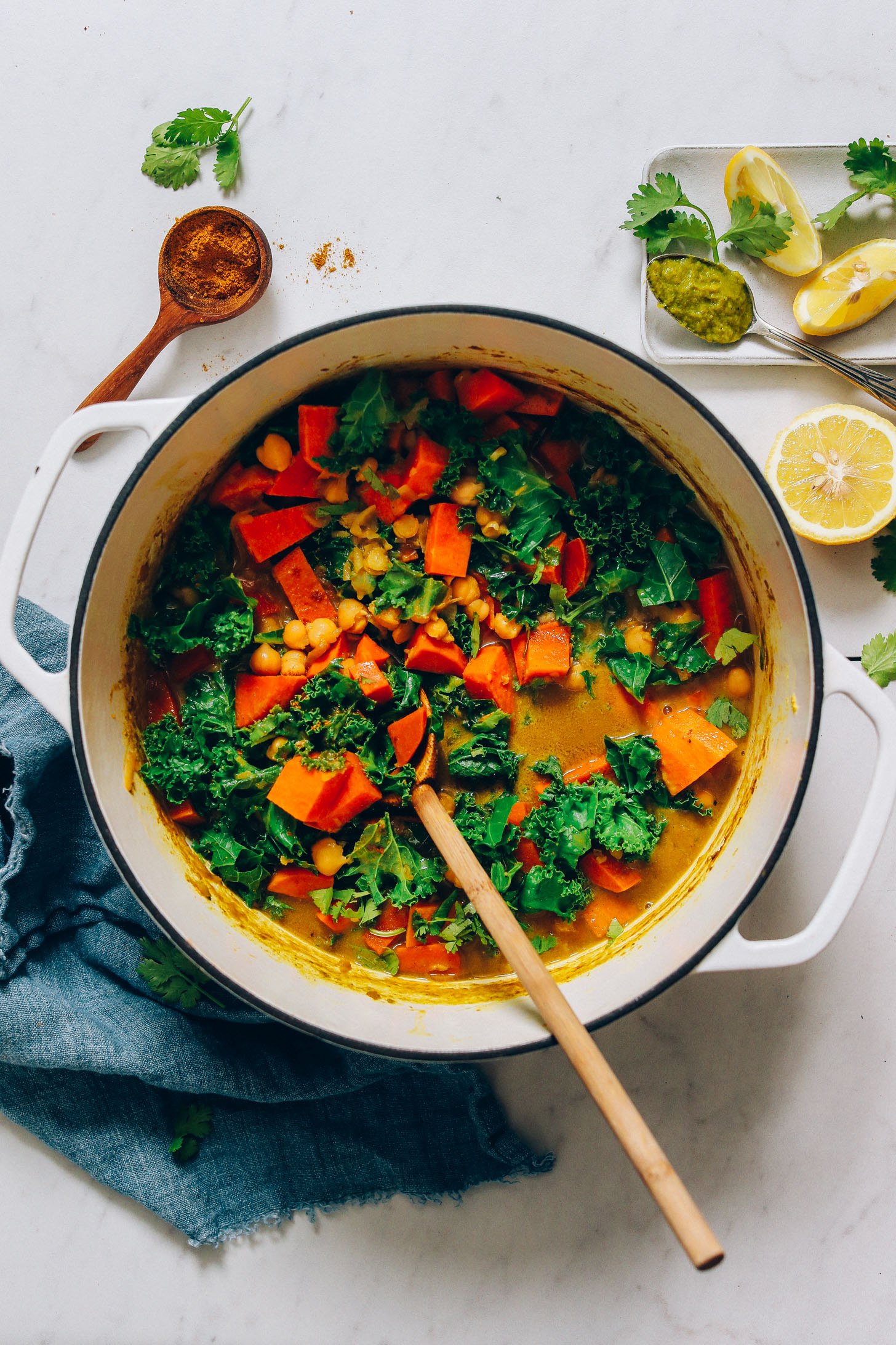 Big pot of vegan Green Curry surrounded by ingredients used to make it