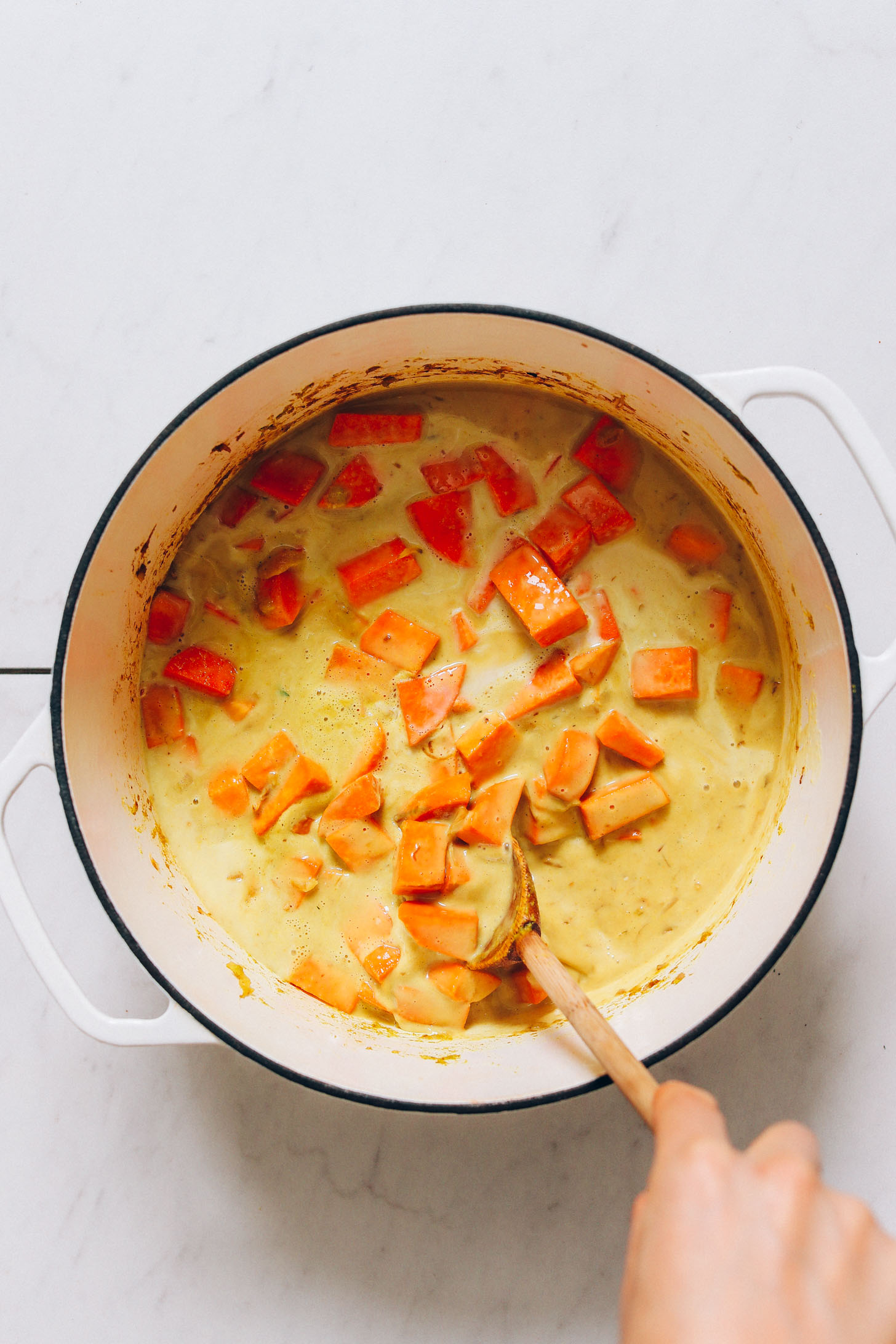Pot of coconut milk, sweet potatoes, and green curry paste