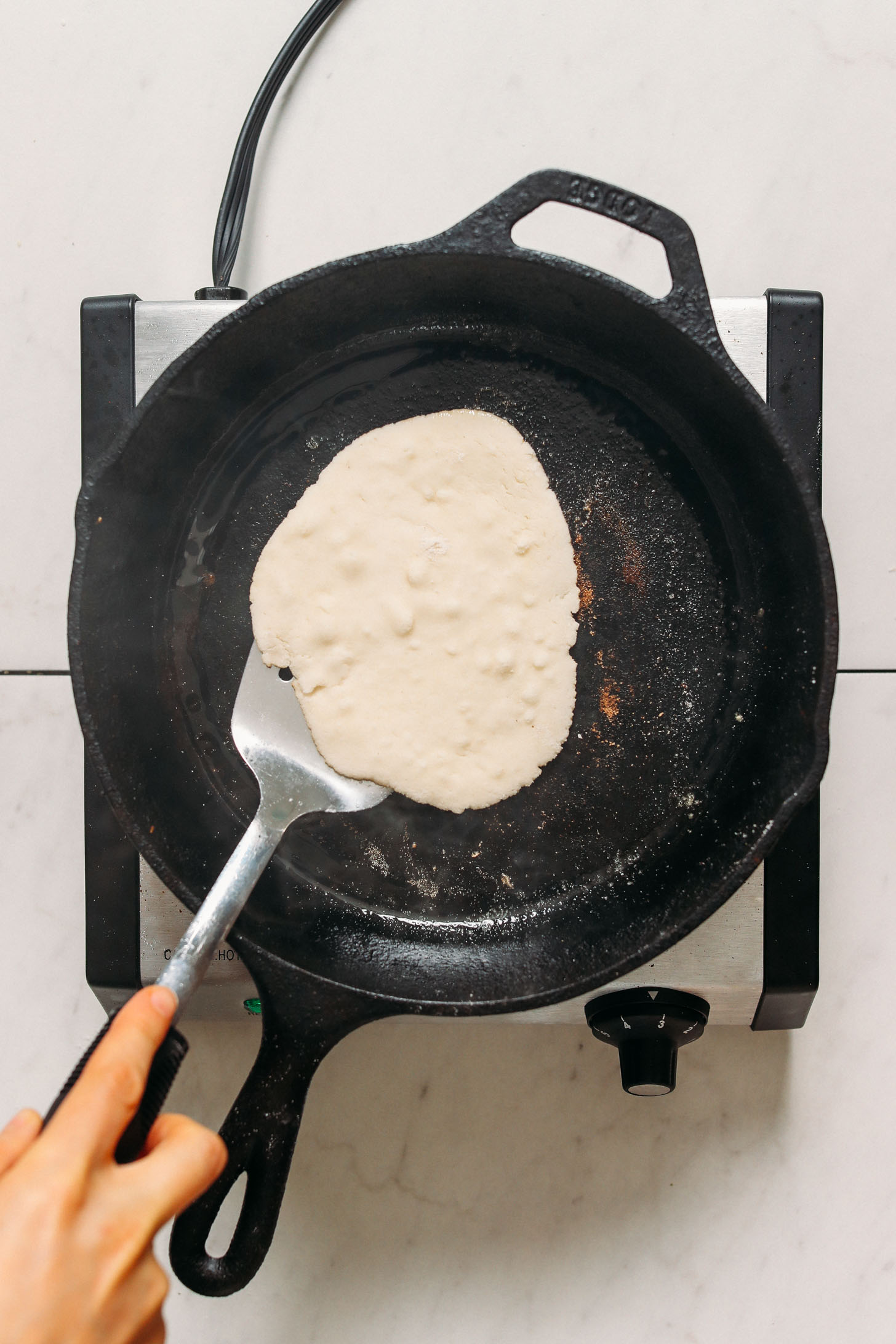 Using a metal spatula to flip a piece of naan bread