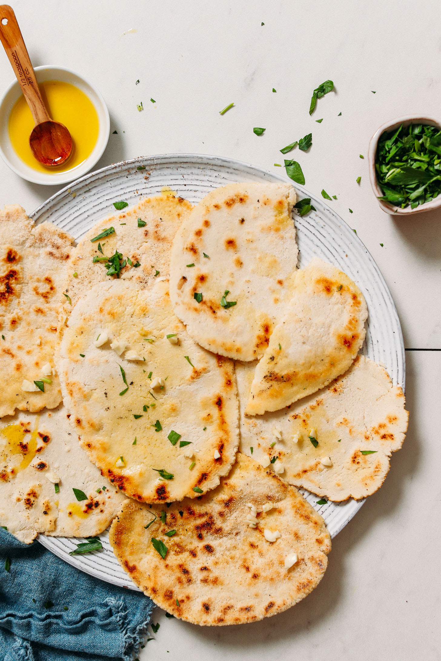 Bowls of olive oil and parsley next to a platter of vegan gluten free naan