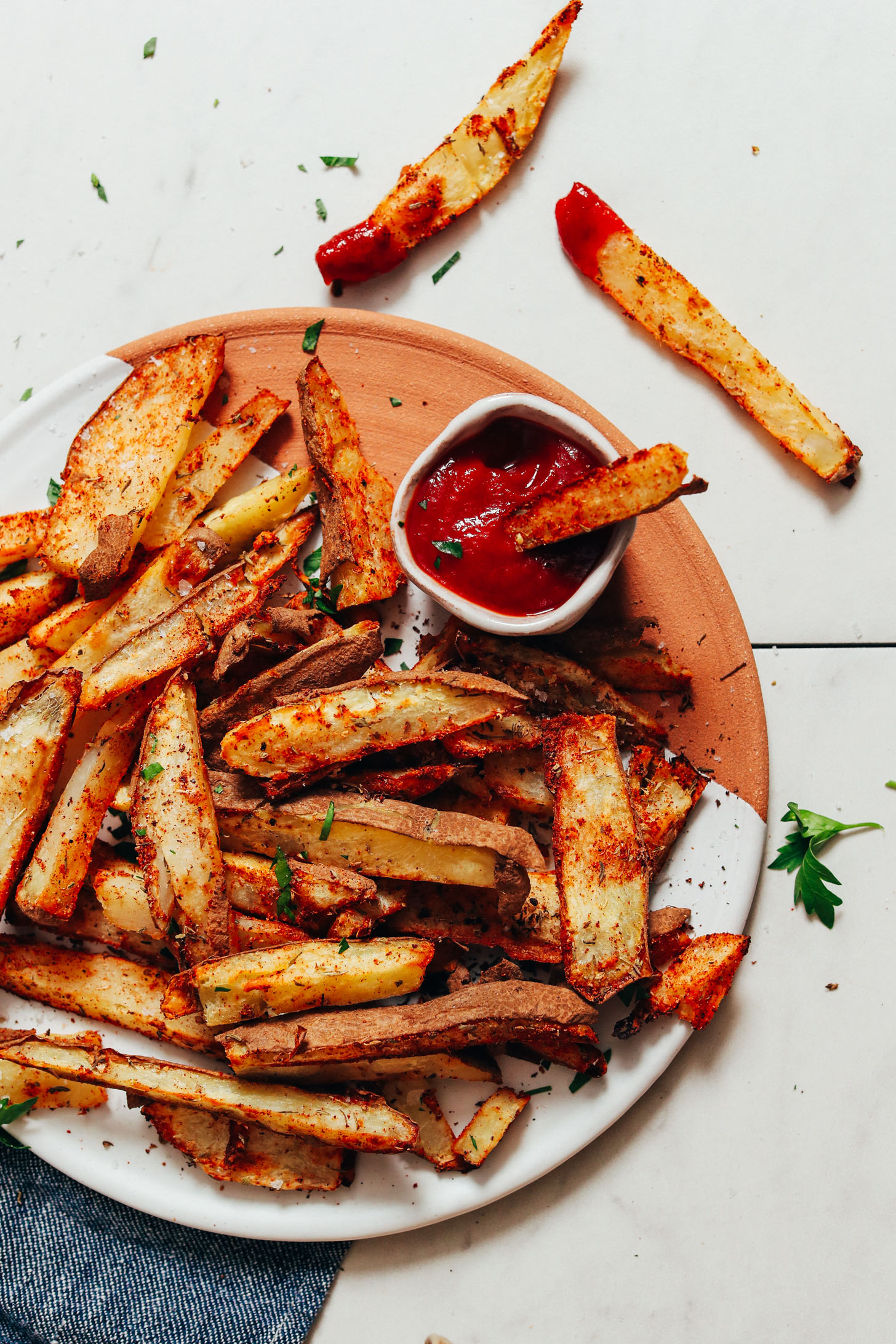 Tray of Oil-Free Cajun Baked Fries with ketchup and fresh parsley