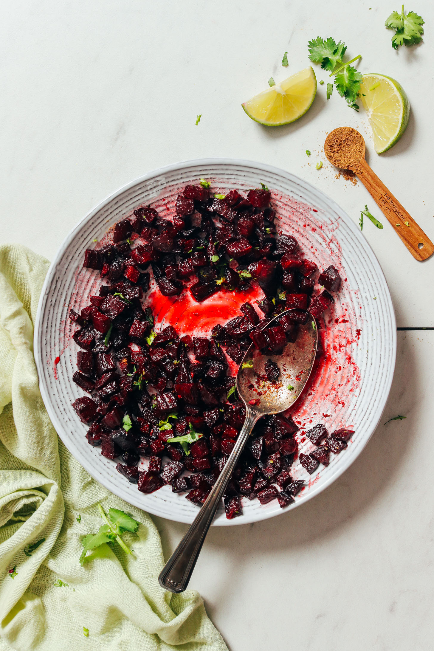 Bowl of Roasted Beet Relish next to cumin, lime wedges, and cilantro