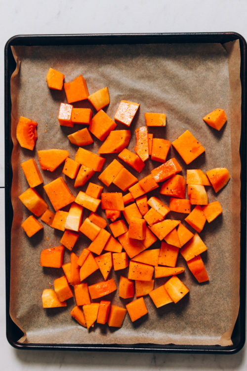 Parchment-lined baking sheet with cubed butternut squash