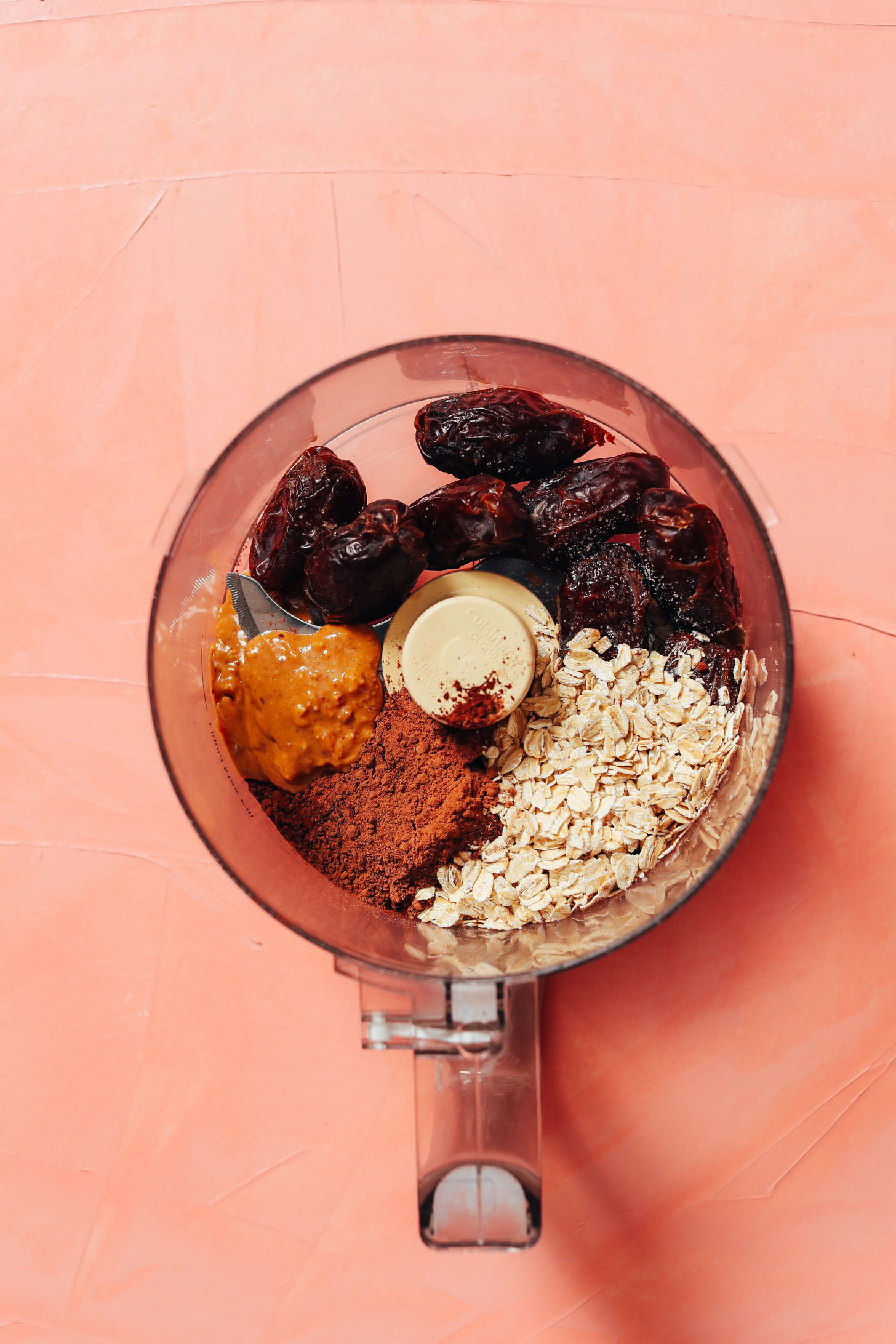 Food processor with pitted dates, oats, cacao powder, and peanut butter