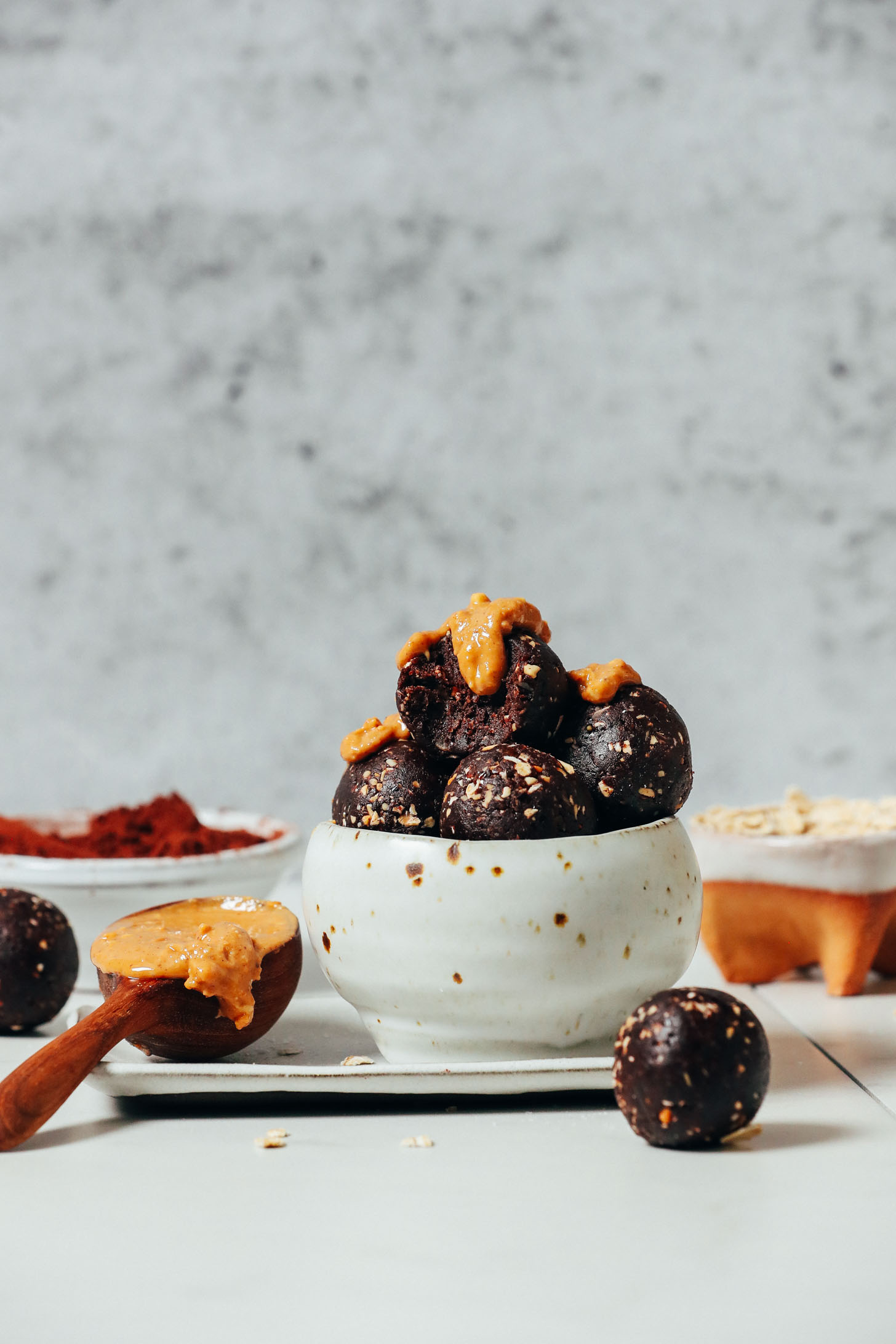 Oats, cacao powder, and peanut butter next to a bowl of Chocolate Energy Bites