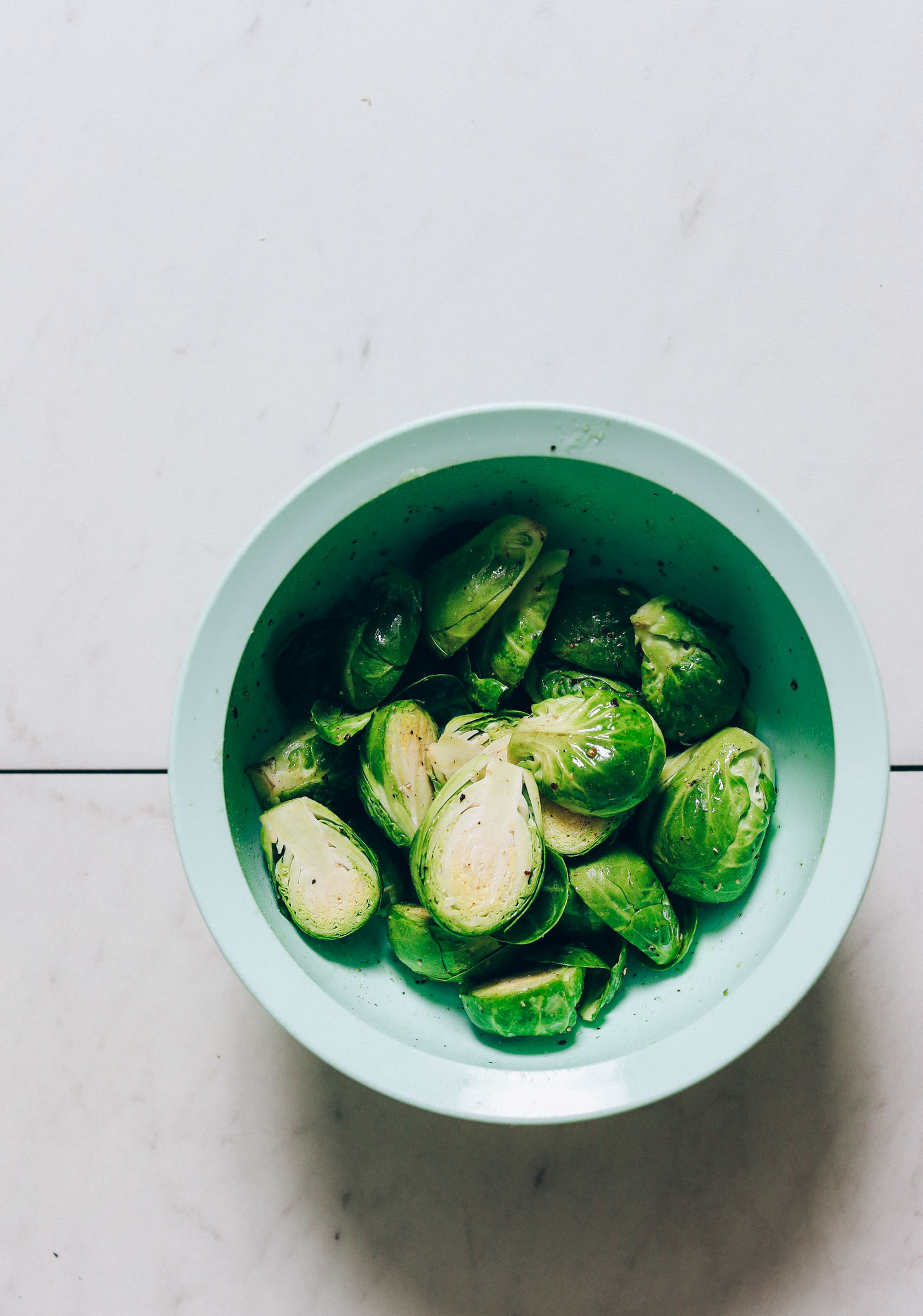 Bowl of halved brussels sprouts with oil and seasonings