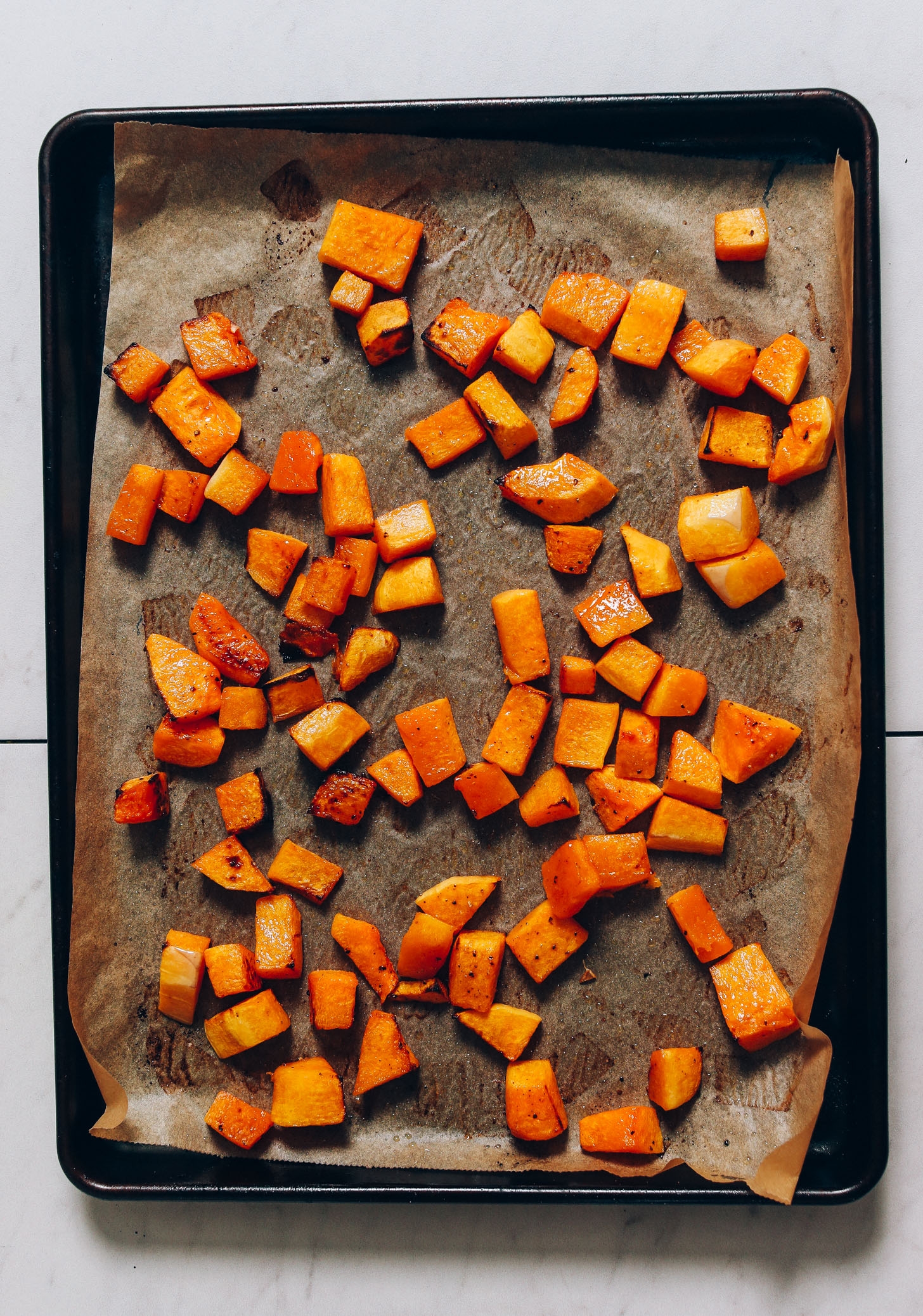 Parchment-lined baking sheet of roasted butternut squash