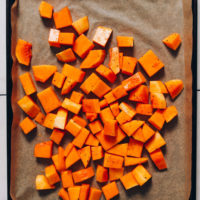 Cubed butternut squash on a parchment-lined baking sheet
