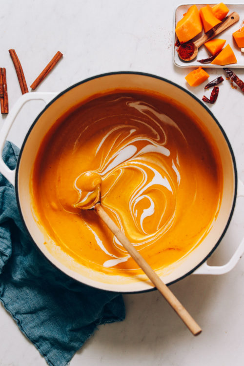 Dutch oven of roasted butternut squash soup with a swirl of coconut milk