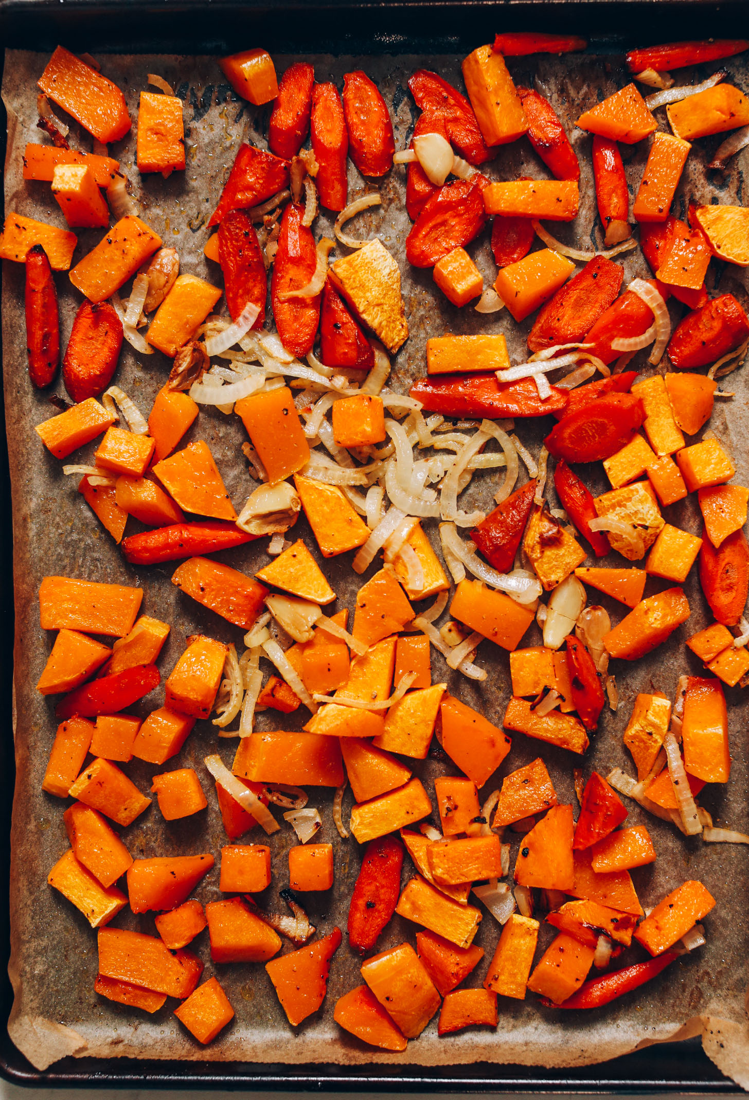 Baking sheet of roasted onion, garlic, carrots, and butternut squash
