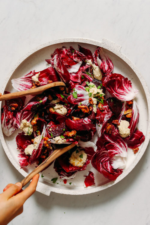 Using salad tongs to pick up a serving of radicchio salad