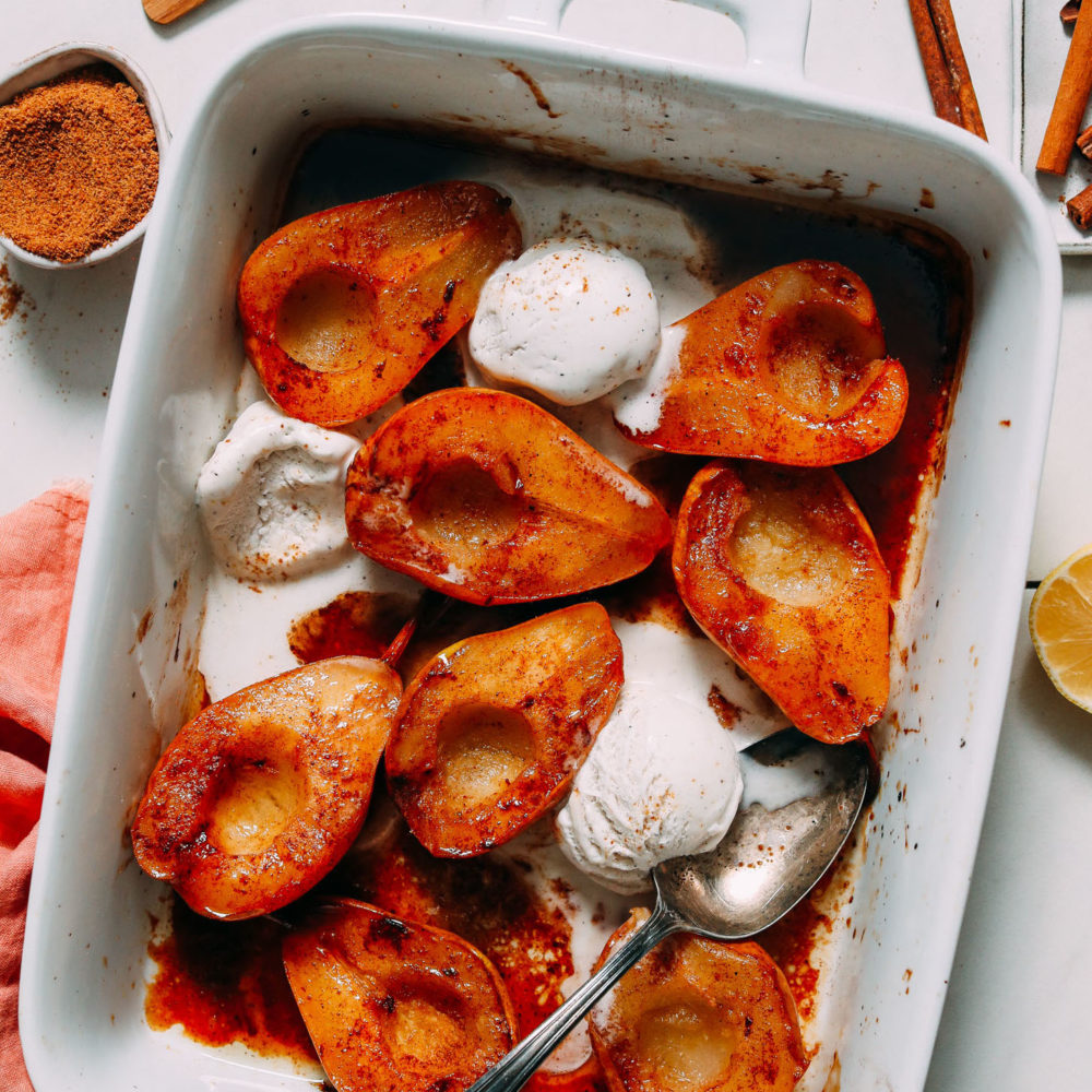 Baking dish filled with cinnamon baked pears with vegan ice cream