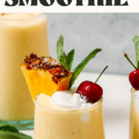 Glasses of our piña colada garnished with coconut whipped cream, a cherry, and a pineapple slice