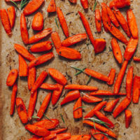 Baking sheet of perfect roasted carrots with fresh rosemary and thyme