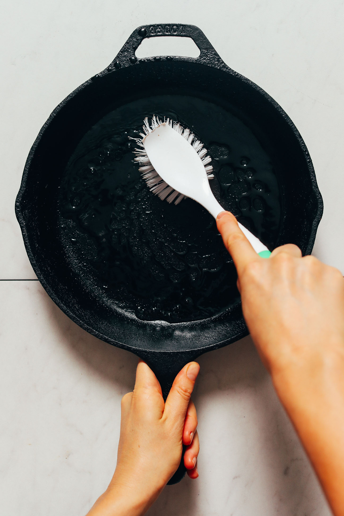 Using a scrub brush to clean a cast iron pan