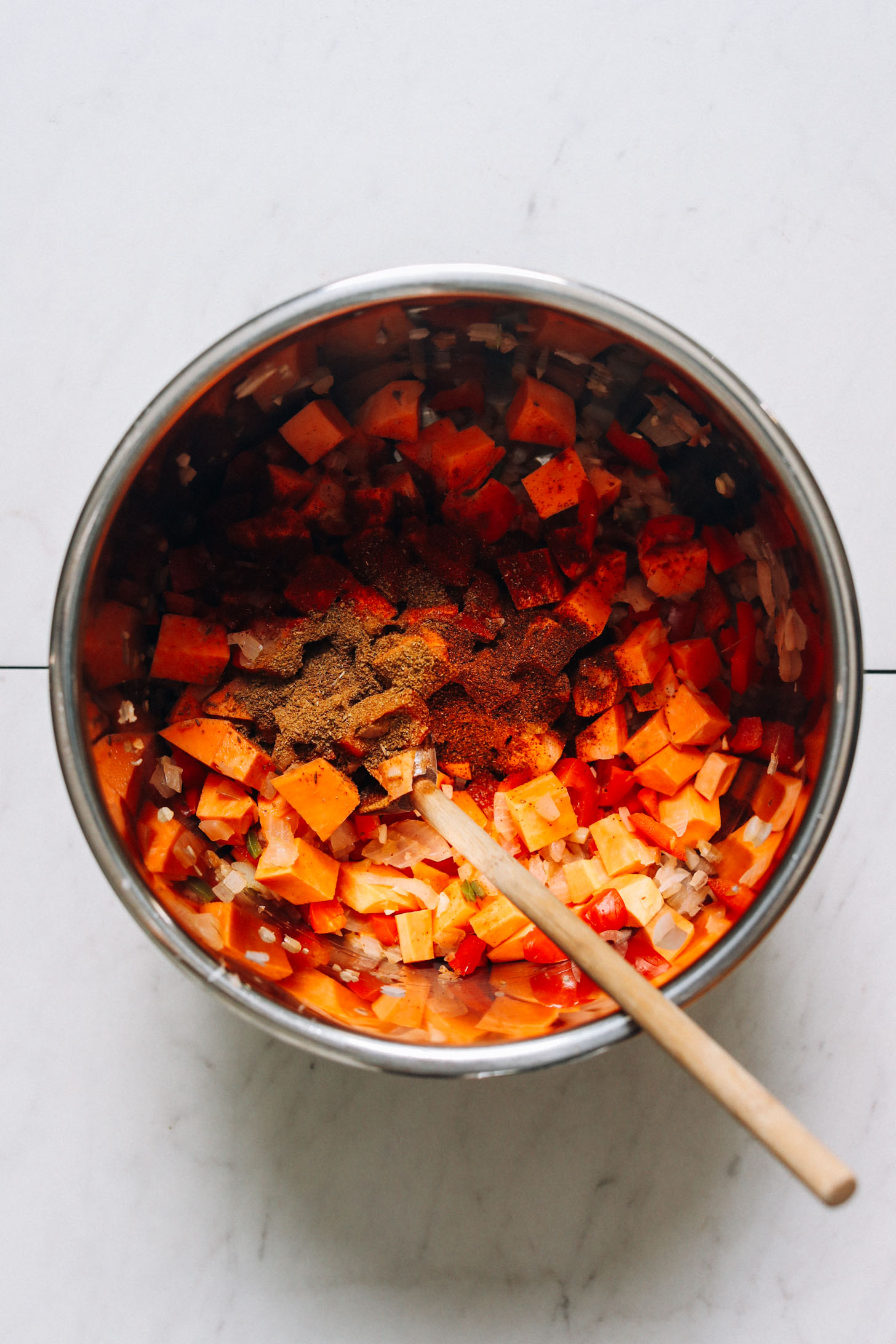 Spices, sweet potato, onion, garlic, and peppers in an Instant Pot