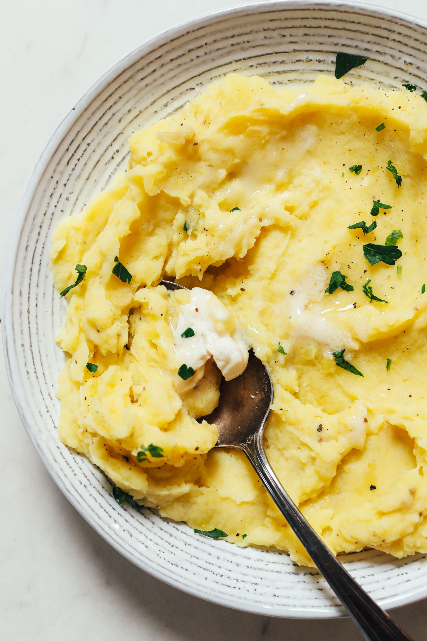 Spoon resting in a bowl of creamy no drain Instant Pot mashed potatoes