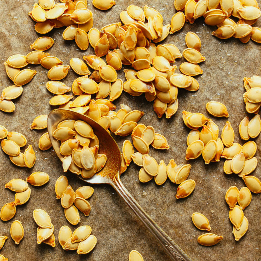 Spoon on a parchment-lined baking sheet of homemade roasted pumpkin seeds