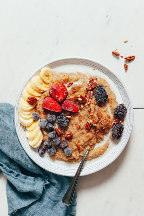 Bowl of amaranth with dairy-free milk, fresh fruit, and pecans