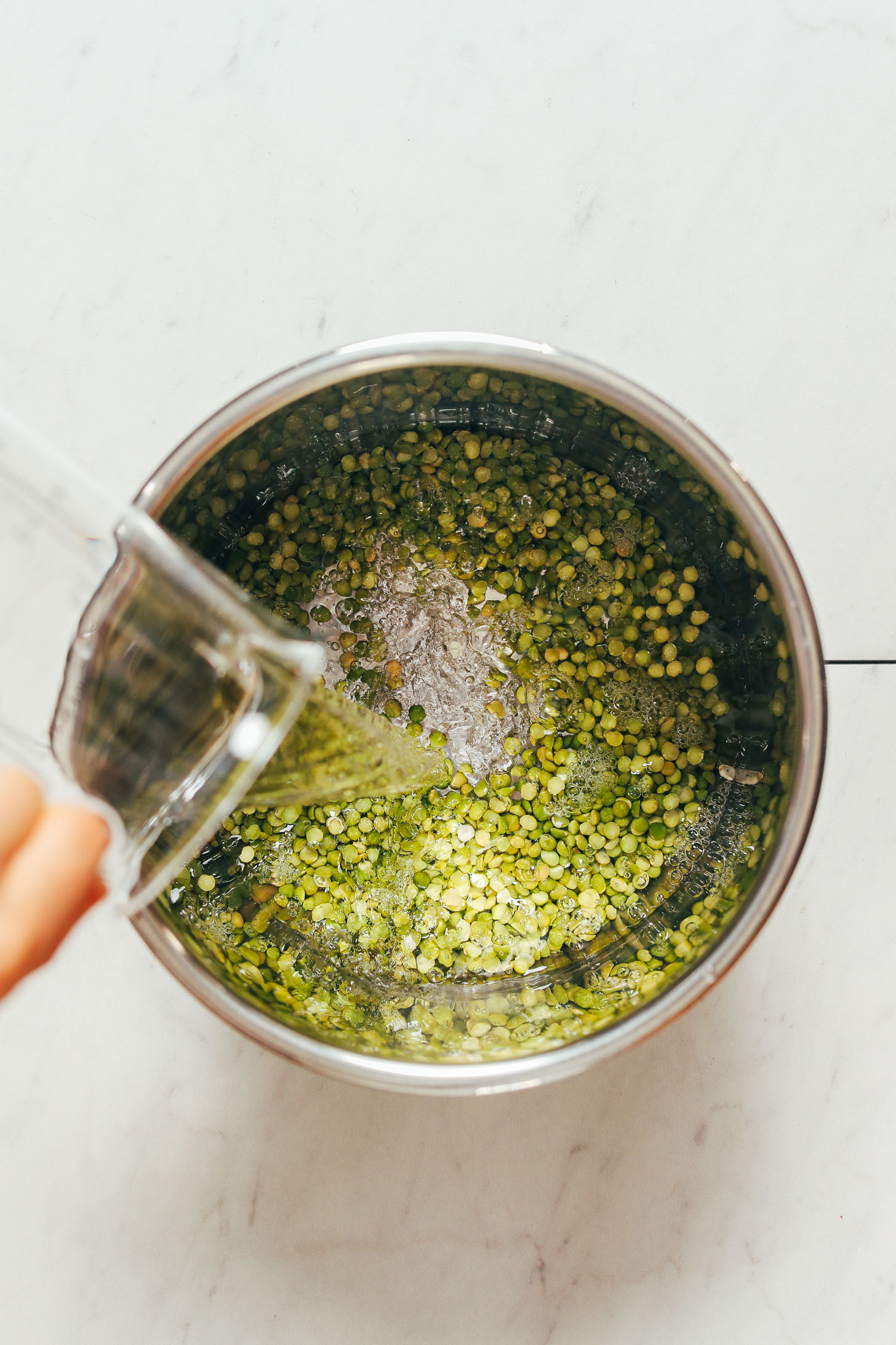 Pouring water into an Instant Pot with green split peas