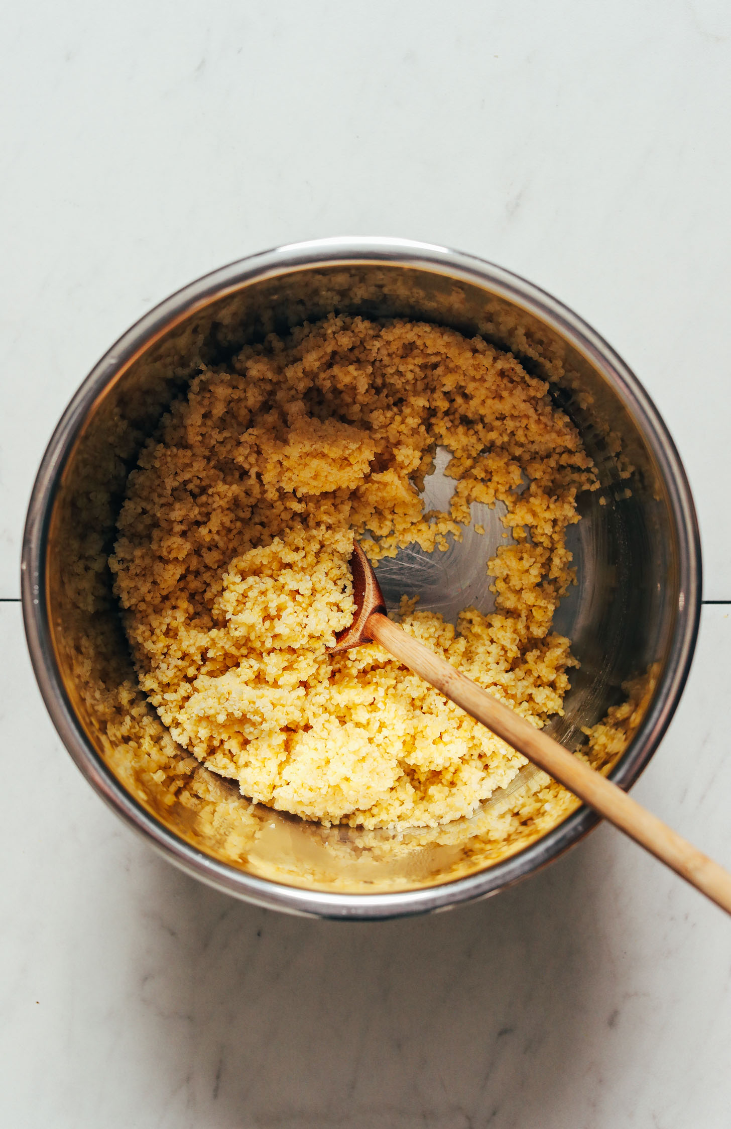 Wooden spoon in an Instant Pot with cooked millet