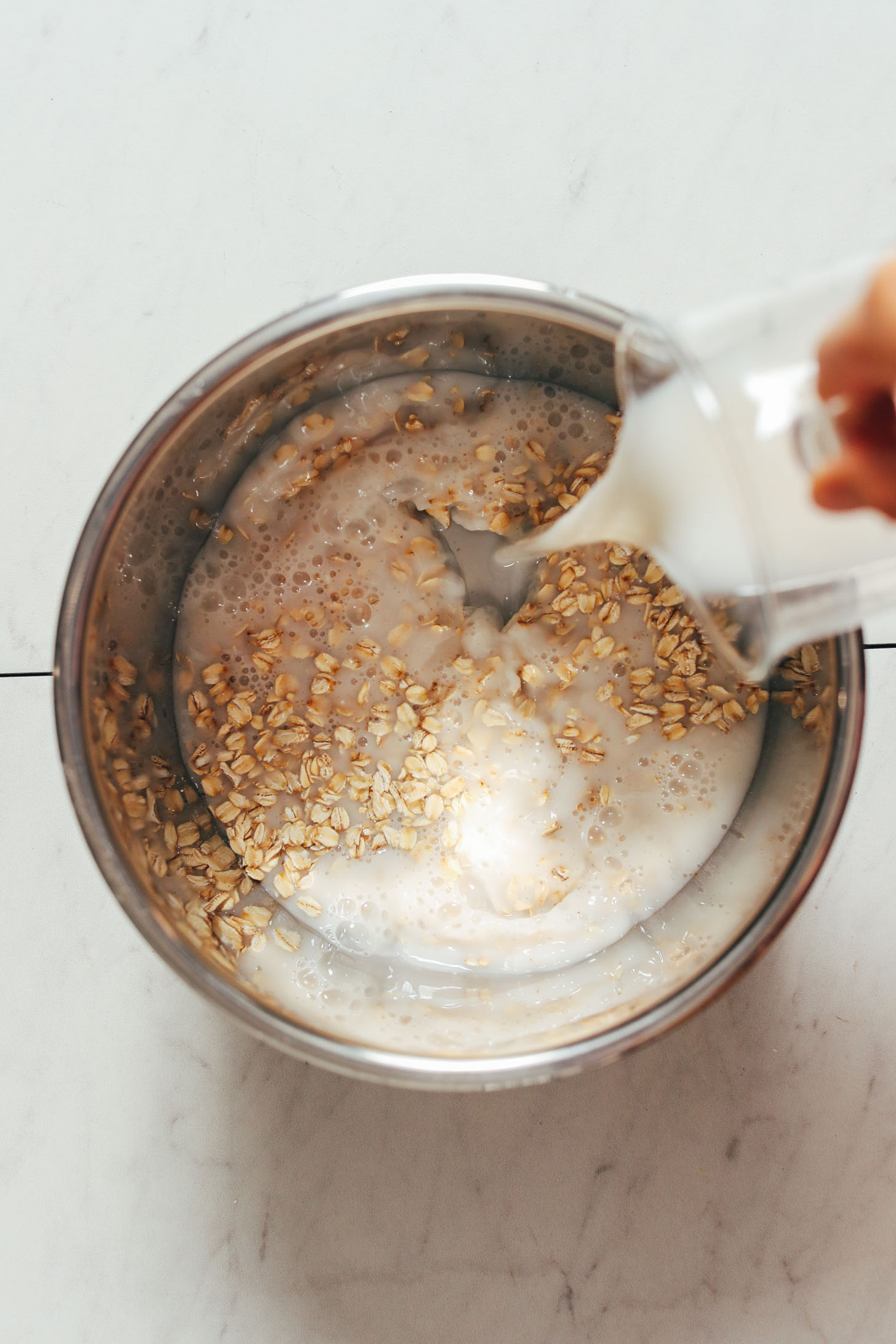 Pouring dairy-free milk into an Instant Pot of oats