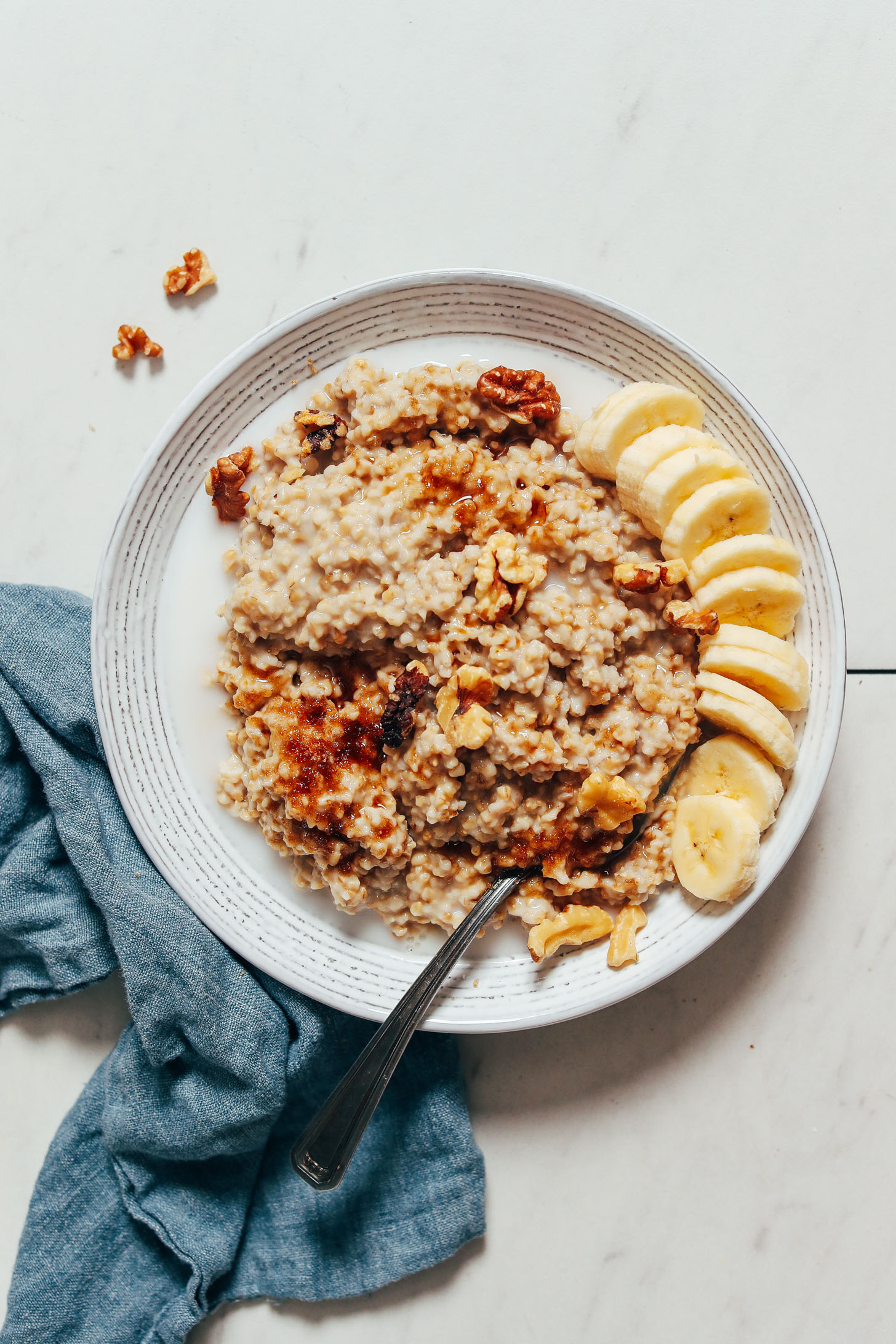 Bowl of Instant Pot steel cut oats with banana, walnuts, brown sugar, and dairy-free milk