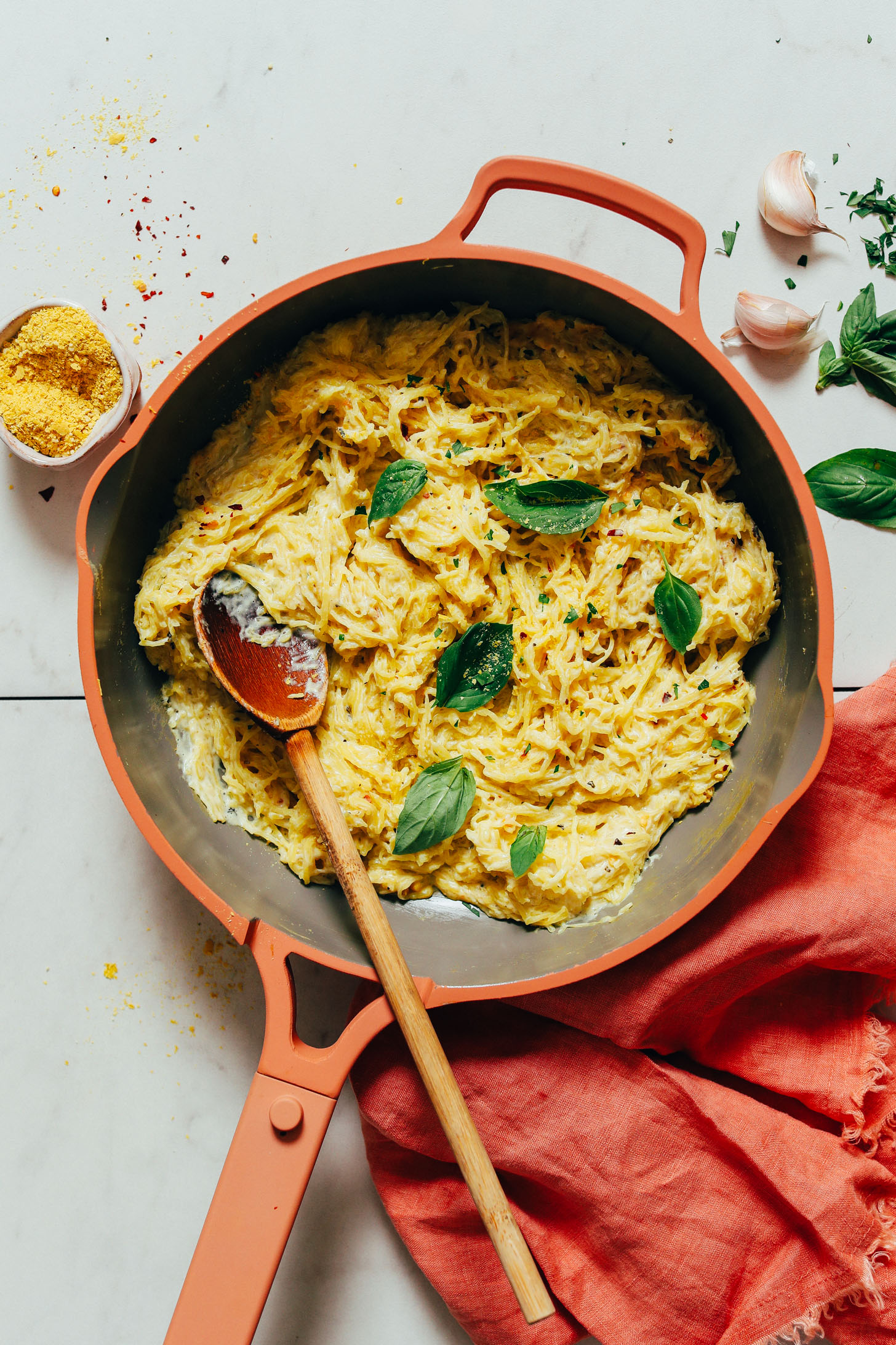 Pan of vegan spaghetti squash alfredo topped with fresh basil leaves