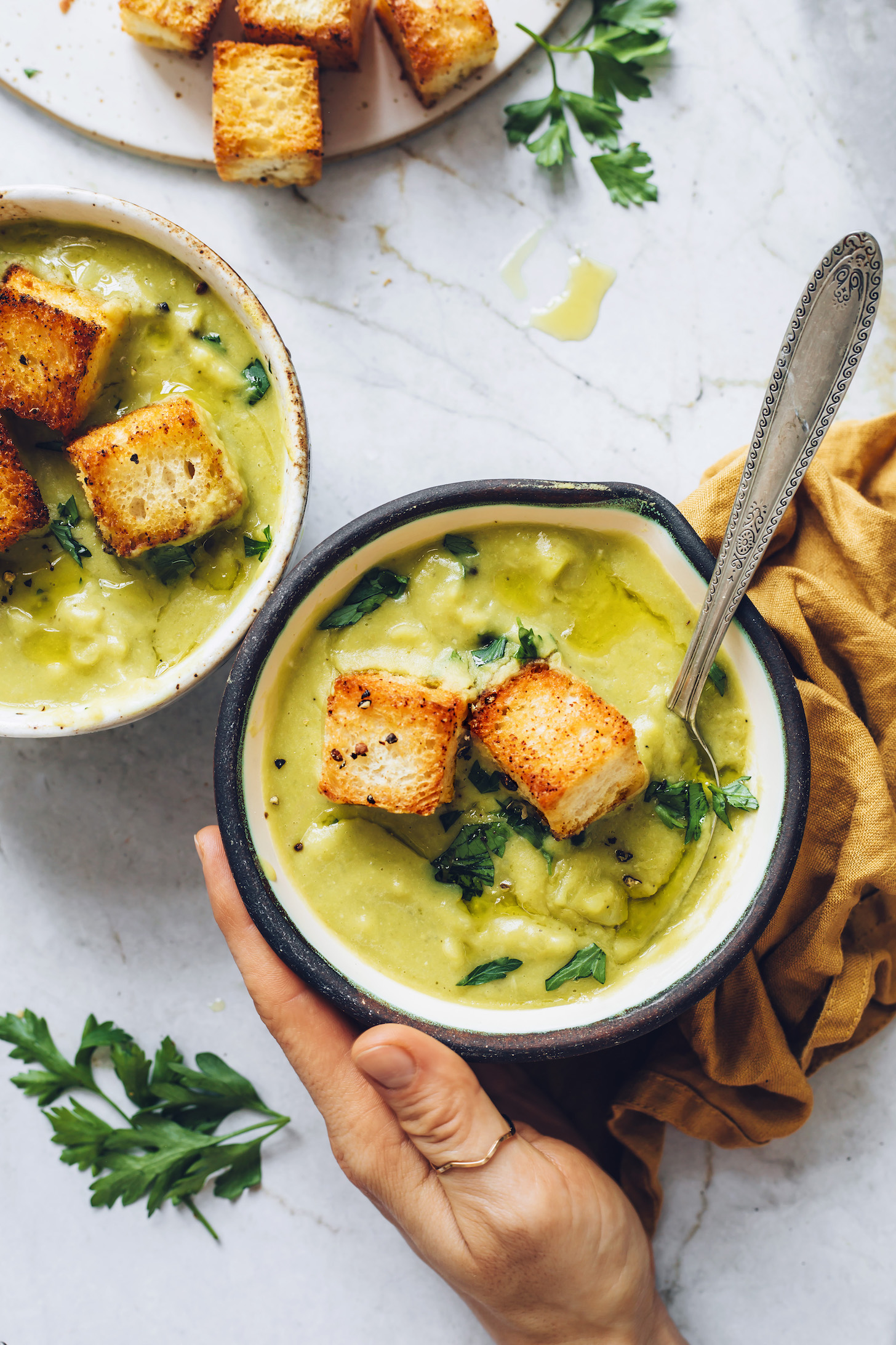 Bowls of creamy green split pea soup topped with croutons