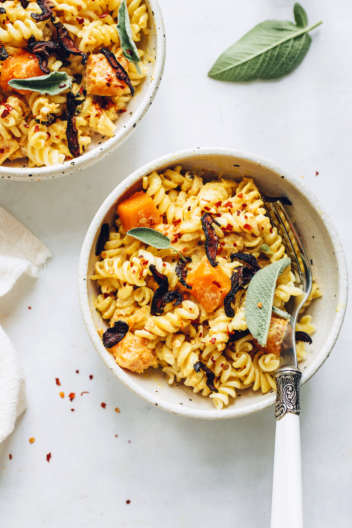 Bowls of butternut squash pasta topped with shiitake bacon and fresh sage
